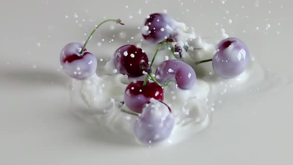 Several Cherry Berries Fall Into the Milk