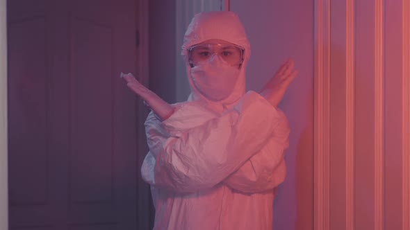 Caucasian Woman in Protective Suit Showing No Crossing Hands Sign alt