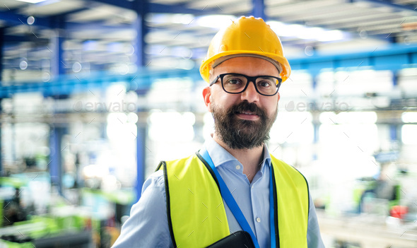 Front view of technician or engineer with hard hat standing in industrial factory