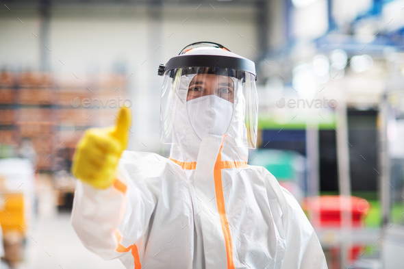 Worker with protective mask and suit in industrial factory, thumb up hand gesture