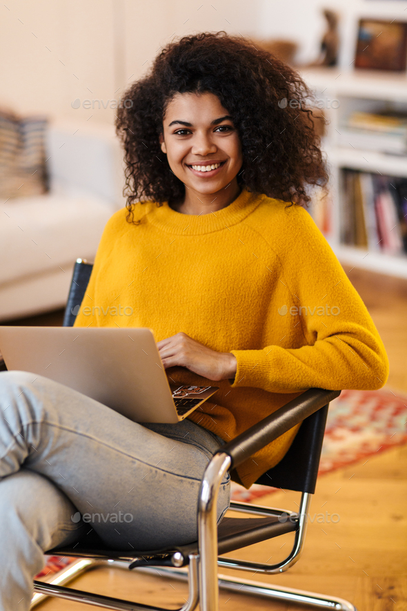 Image of african american woman using laptop while sitting on chair