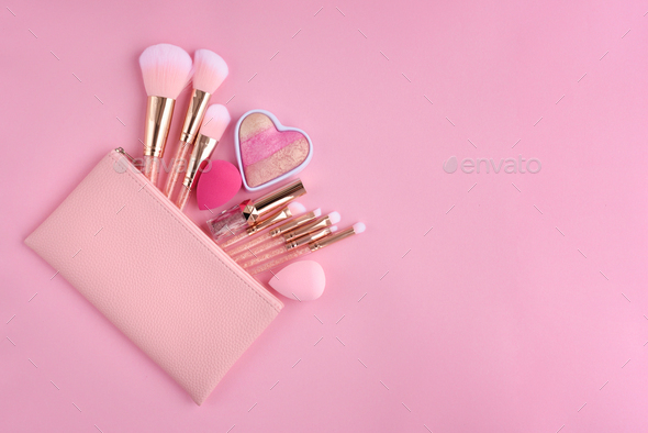 A pink cosmetics bag with make-up brushes and makeup products