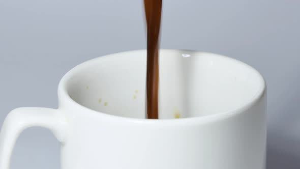 Pouring Black Coffee Into a White Cup