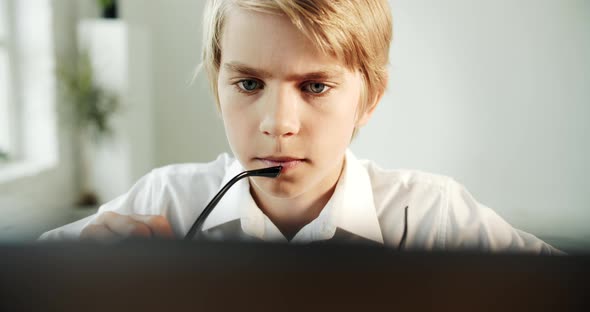 Focused Boy in Eyeglasses Typing on Laptop