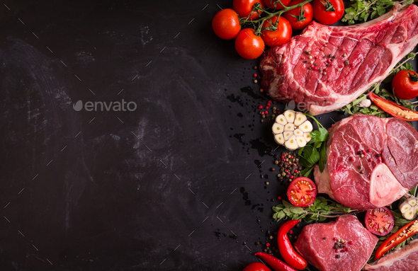 Raw meat steaks on a dark background ready to roasting - Stock Photo - Images