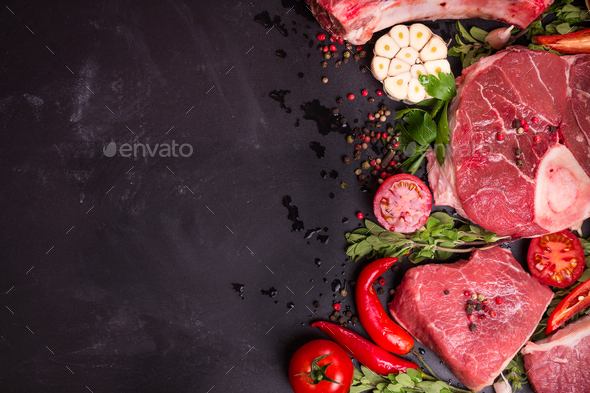 Raw meat steaks on a dark background ready to roasting - Stock Photo - Images