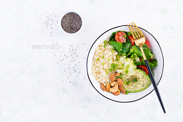 Vegan Buddha bowl with bulgur, avocado, cucumber, lettuce, tomatoes and chia seeds - Stock Photo - Images