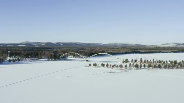 Aerial View of a Bridge Over a River in the Woods in Winter alt