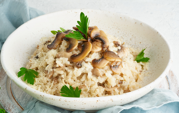 Risotto with mushrooms in plate. Rice porridge with mushrooms and parsley - Stock Photo - Images