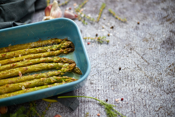 Roasted asparagus seasoned with salt, pepper, garlic and decorated with fresh herbs - Stock Photo - Images