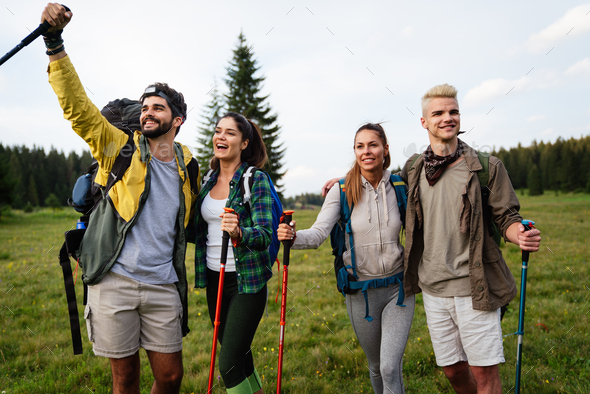 Trekking, hiking, camping and wild life concept. Group of friends walking together in nature
