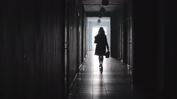 Silhouette of Businesswoman Walking along Corridor