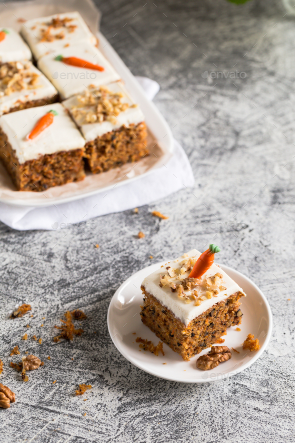 pieces of carrot cake with walnuts with icing cream on a light background