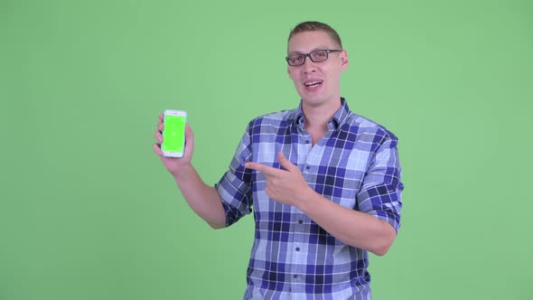Happy Young Hipster Man Showing Phone and Giving Thumbs Up alt