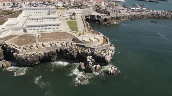 Aerial pan shows historic Peniche Fortress on rocky cliffs of Atlantic