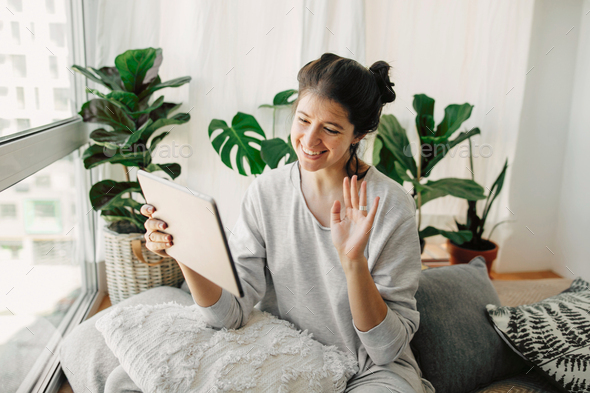 Happy hipster girl chatting on tablet, communicating live with family from home - Stock Photo - Images