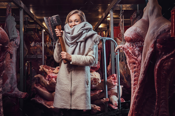 Blond female in a warm jacket in a meat freezer storage.
