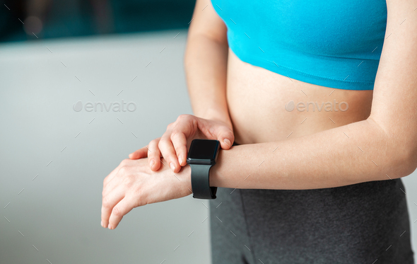 Closeup of woman with smart watch in gym, blank space for design