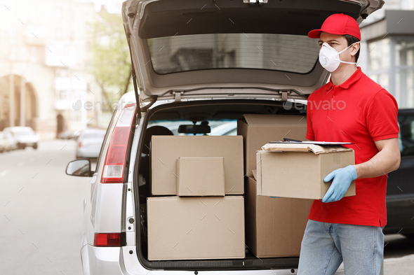 Delivery man wearing prevention mask and gloves is holding stack