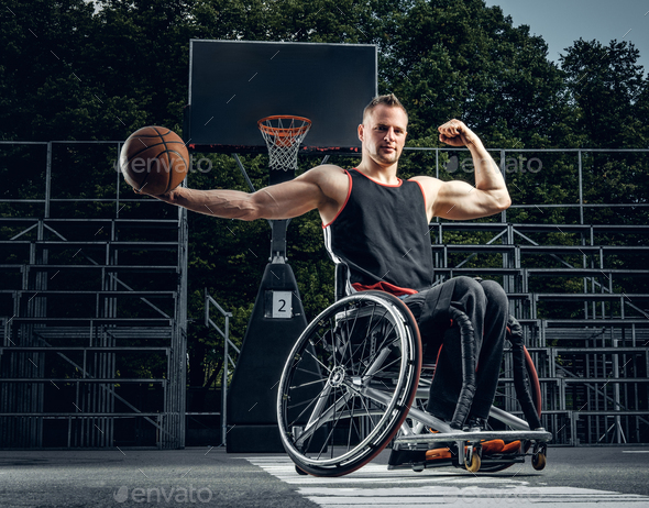 Cripple basketball player in wheelchair holding ball.