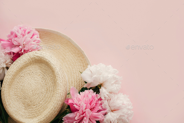Straw hat with white and pink peonies on pastel pink paper, flat lay - Stock Photo - Images