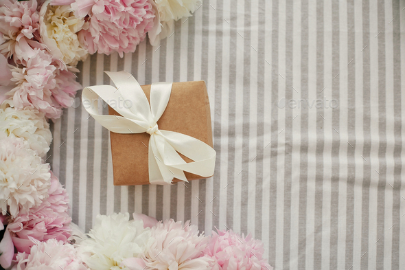 Craft gift box and peonies frame flat lay on rustic table cloth - Stock Photo - Images