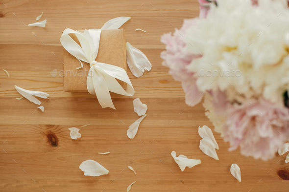 Beautiful peonies in vase and gift box on rustic wooden table top view - Stock Photo - Images