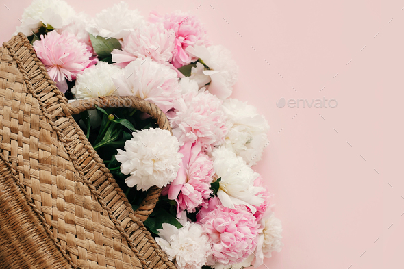 Stylish straw rustic bag with white and pink peonies on pastel pink paper - Stock Photo - Images