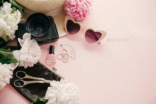 Stylish girly flat lay with pink peonies, photo camera, retro sunglasses, jewelry