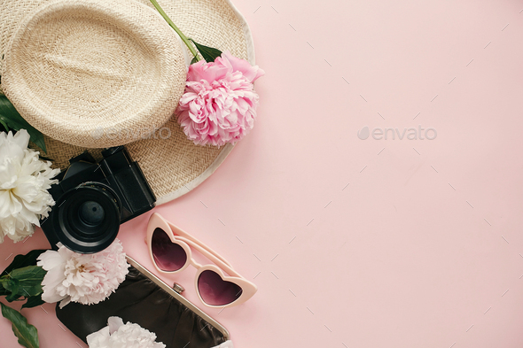 Stylish girly image of peonies, photo camera, retro sunglasses, hat, purse on pastel pink paper - Stock Photo - Images