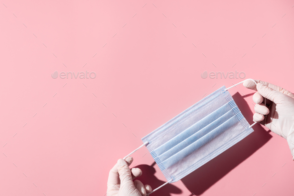 Woman hands in latex gloves holding facial medical mask, pink background, close up, copy space - Stock Photo - Images