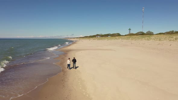 Two women are walking along the beach, view from a drone alt
