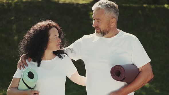 Sporty Man and Woman Are Standing with Mas in a Park alt