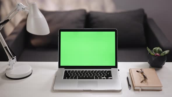 Green Screen Laptop Computer on Home Work Desk Next to Desk Lamp