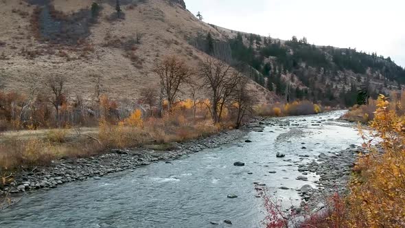 Ariel drone footage of a rugged river valley in fall. alt
