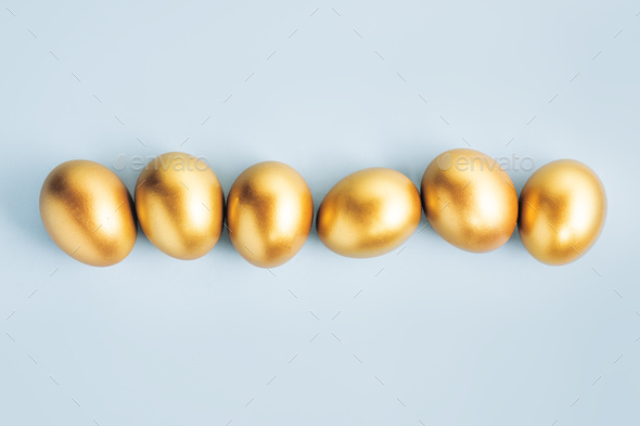 Golden eggs on blue pastel background