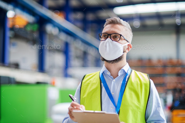 Technician or engineer with protective mask working in industrial factory, walking