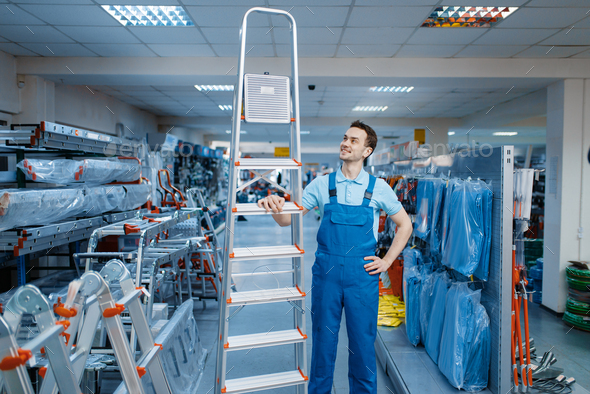Worker holds aluminum stepladders in tool store - Stock Photo - Images