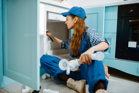Female plumber fixing problem with drain pipe - Stock Photo - Images