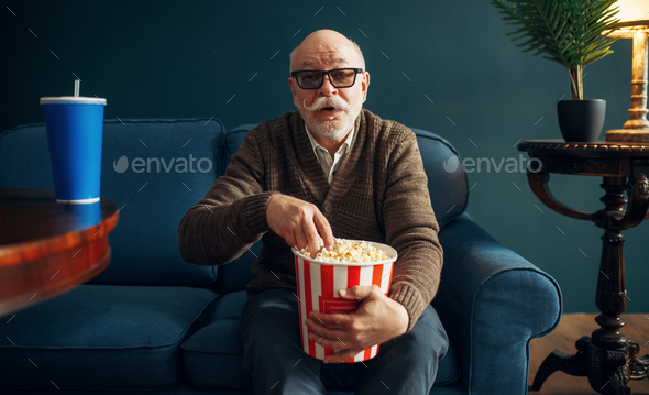 Elderly man with popcorn watching TV on couch