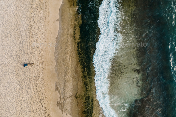 Aerial view of sand meeting the sea water and waves