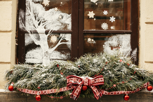 Stylish christmas snowy fir branches with festive red bow and balls on window store - Stock Photo - Images