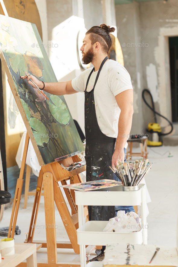 Bearded Male Artist Painting on Easel in Workshop
