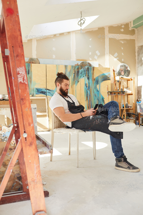 Contemporary Male Artist Using Smartphone in Workshop - Stock Photo - Images
