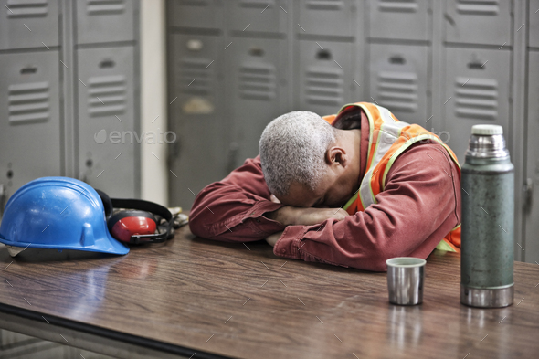 Black man factory worker taking a break from work in a factory locker room.