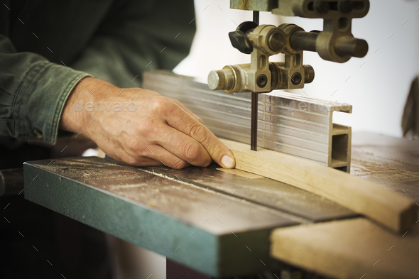 A craftsman using a machine drill on a piece of smooth planed shaped wood.