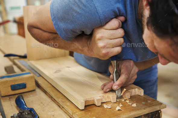 Close up of man working a boat-builder\'s workshop, joining together two pieces of wood.