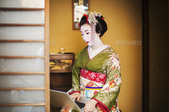 A woman dressed in the traditional geisha style, wearing a kimono and obi, with an elaborate - Stock Photo - Images