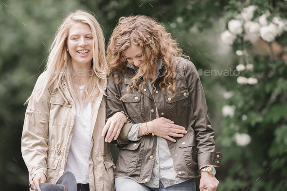 Two women walking arm in arm in the countryside. - Stock Photo - Images