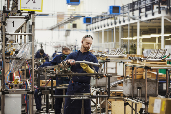 A man wearing one protective glove with sunglasses on his head, skilled factory worker working on - Stock Photo - Images